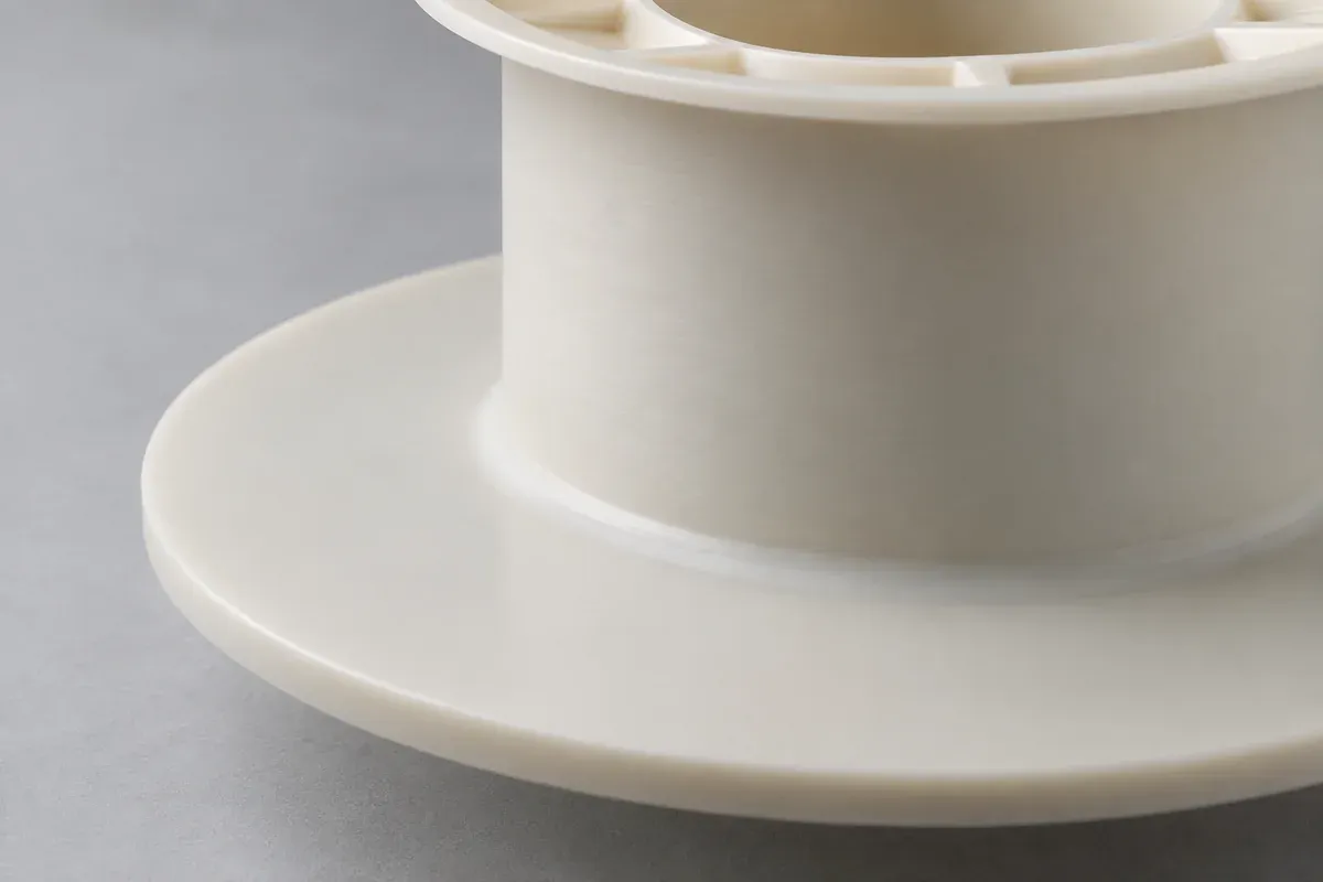Close view of a plastic bobbin barrel and the root of its end flange