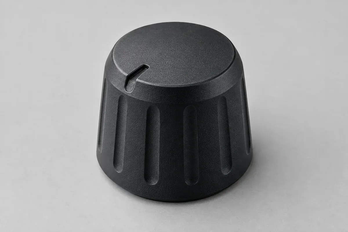 Molded radial index notch on the top face of a dark plastic control knob