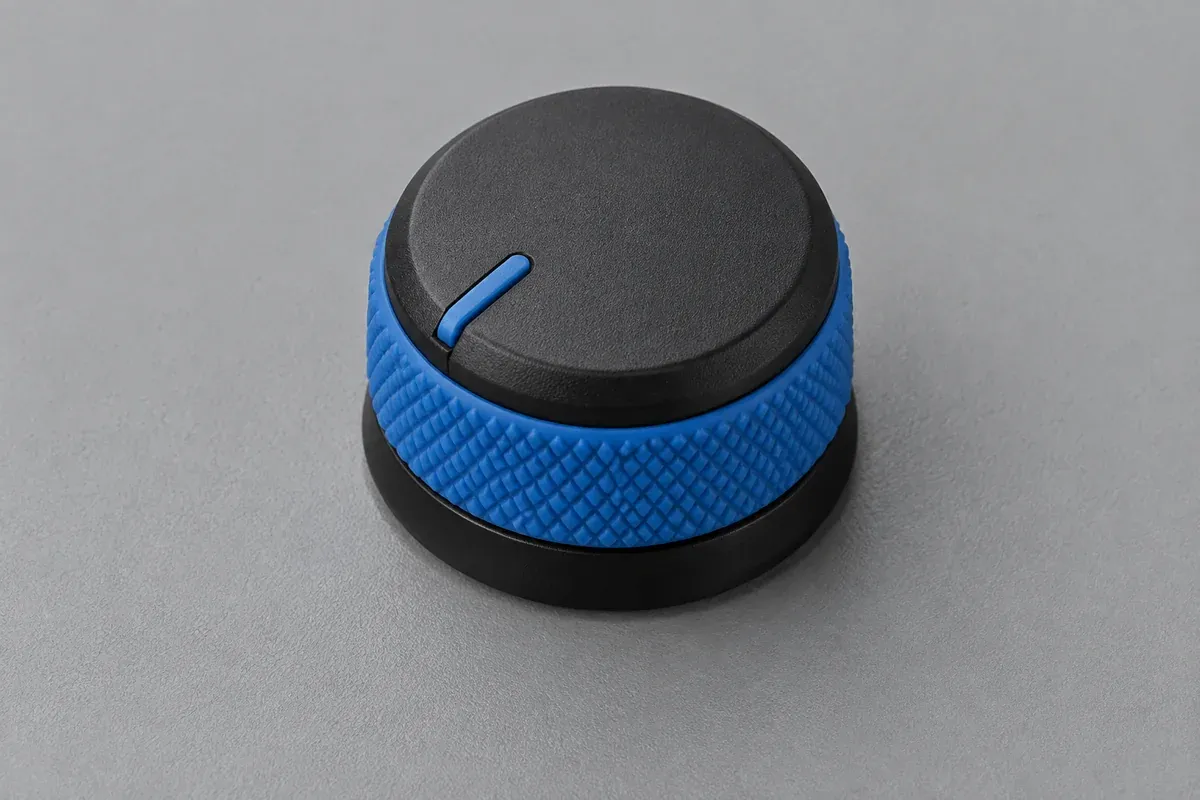 Plastic control knob with a contrasting soft grip band mounted on a plain panel