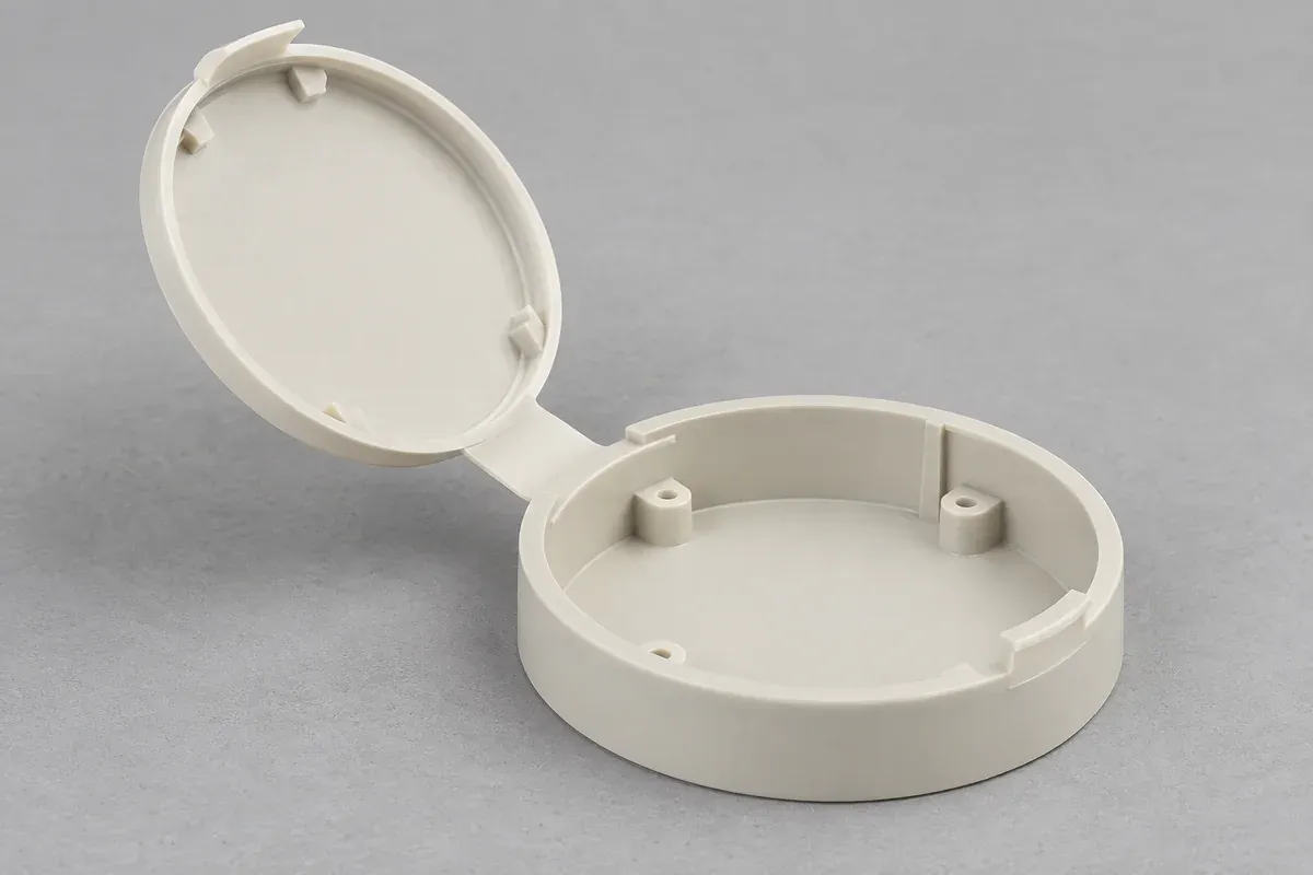 Open circular plastic cover with an integral flexible connection